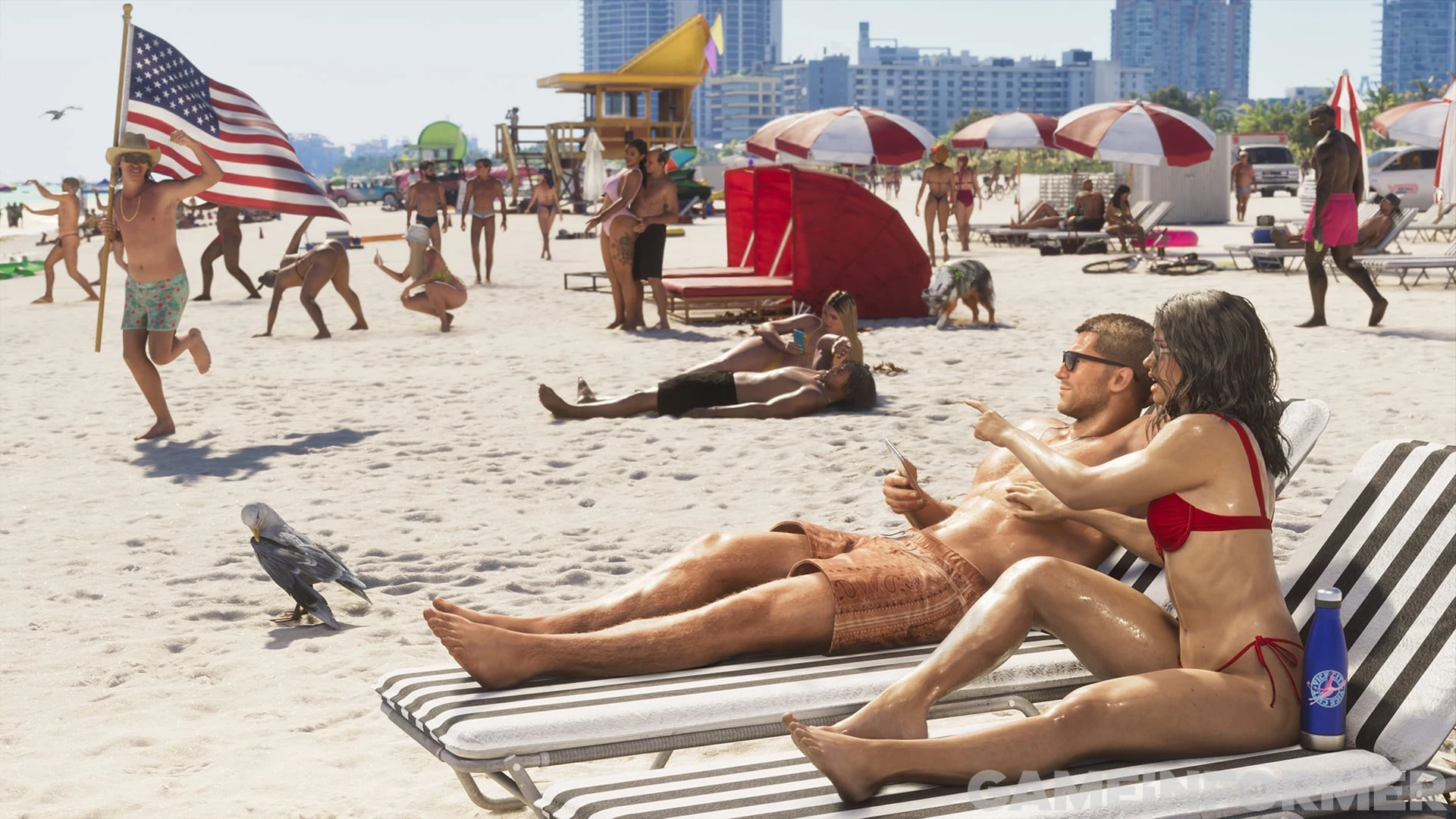 Capture de GTA VI publiée par Game Informer : une plage bondée de Vice City, un couple sur des transats au premier plan, parasols et drapeau américain derrière