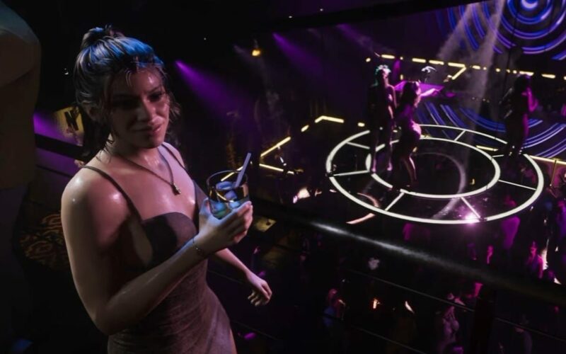 Lucia, un verre à la main, sur la mezzanine d’une boîte de nuit de Vice City éclairée de violet dans GTA VI