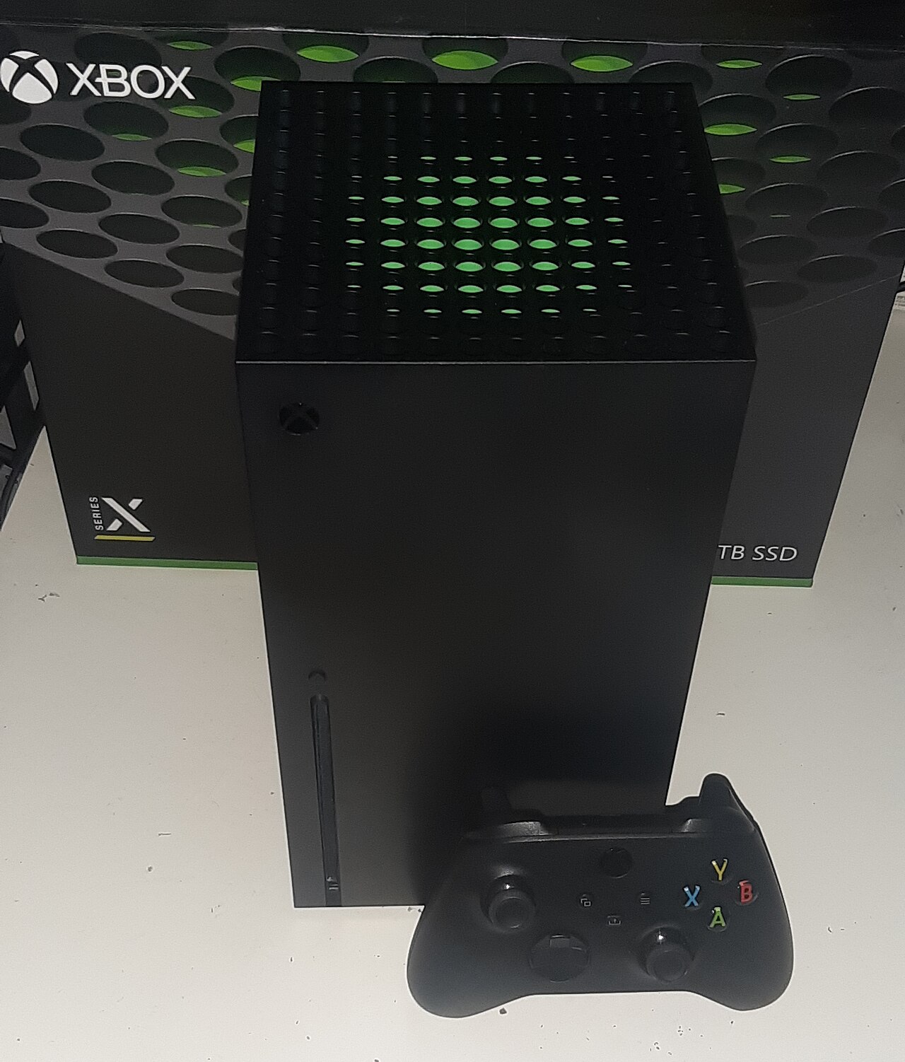 Console Xbox Series X noire posée verticalement avec sa manette