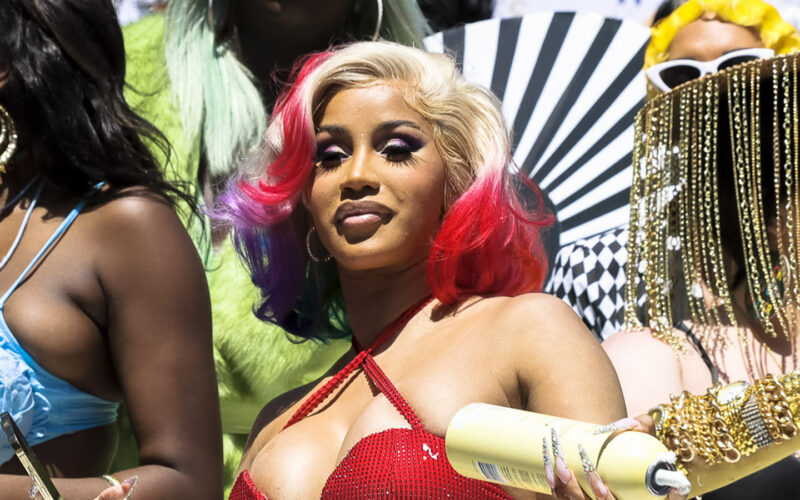 La rappeuse Cardi B, cheveux blonds et rouges, en haut rouge, lors d’une parade en plein air