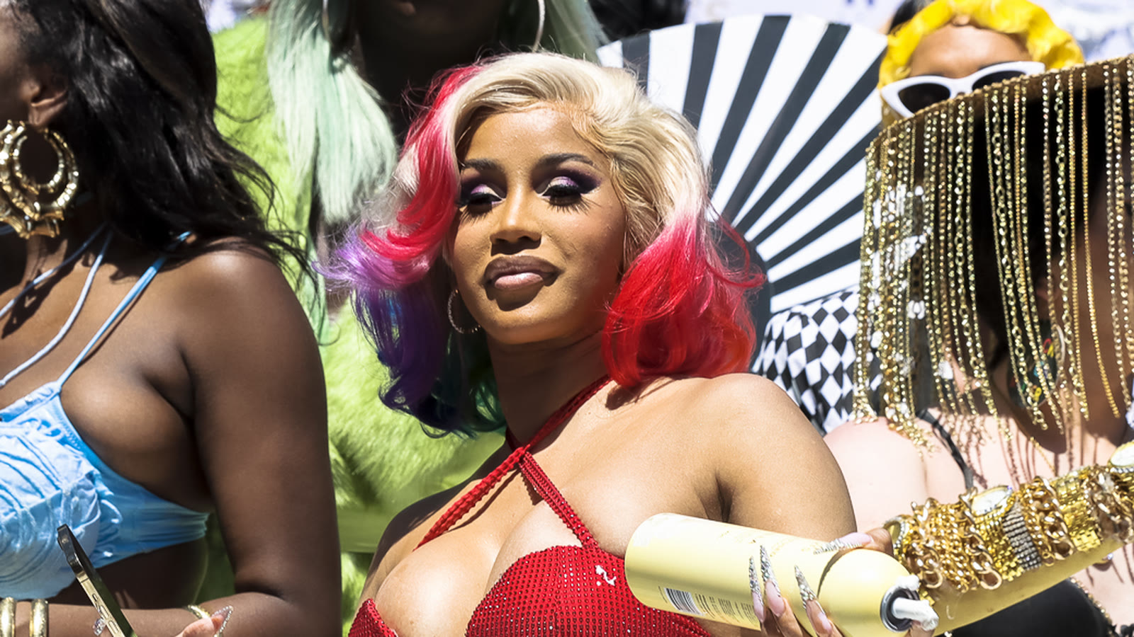 La rappeuse Cardi B, cheveux blonds et rouges, en haut rouge, lors d’une parade en plein air