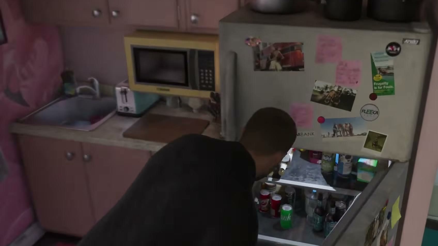 Jason ouvre le réfrigérateur couvert d’aimants, dont un aimant Fleeca, dans la cuisine rose de l’appartement, dans l’Extended Look de GTA VI