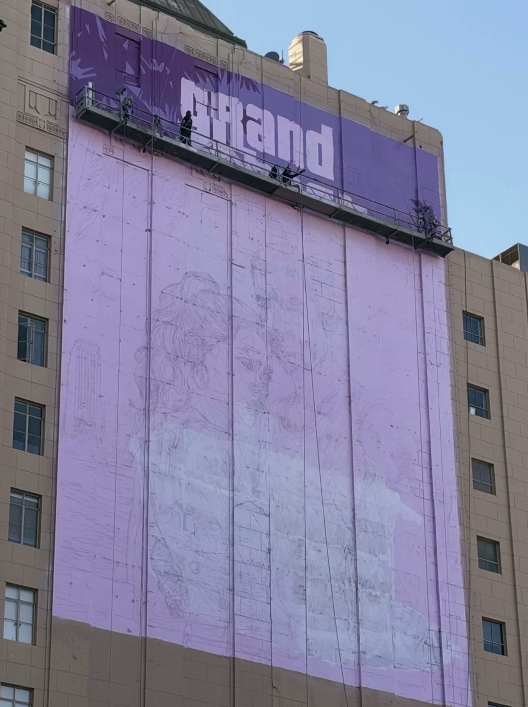 Façade d’immeuble peinte en violet sur Hollywood Boulevard, avec le mot Grand et l’esquisse de Jason et Lucia