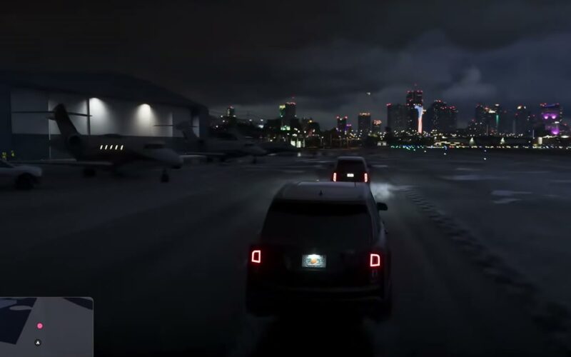 Un SUV roule de nuit sur le tarmac de l'aéroport de Vice City, entre hangars et jets privés, la skyline au loin, dans GTA VI
