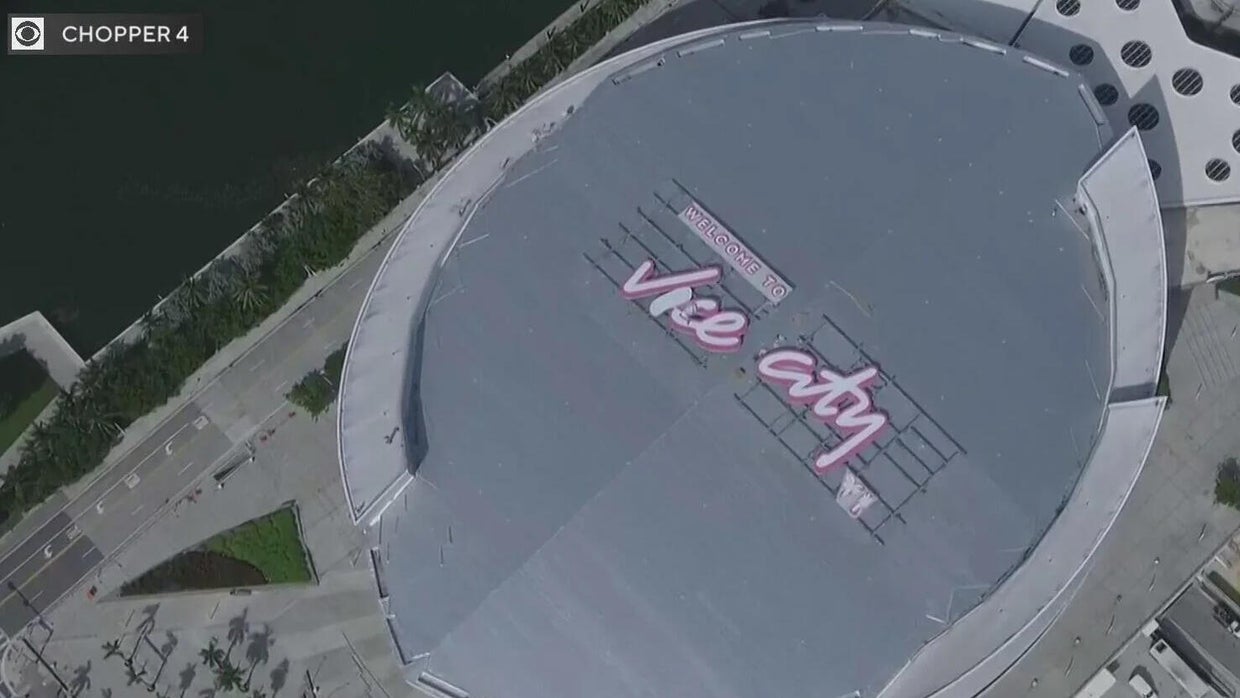 Vue aérienne du Kaseya Center de Miami avec le panneau rose « Welcome to Vice City » de GTA VI sur son toit, au bord de la baie de Biscayne