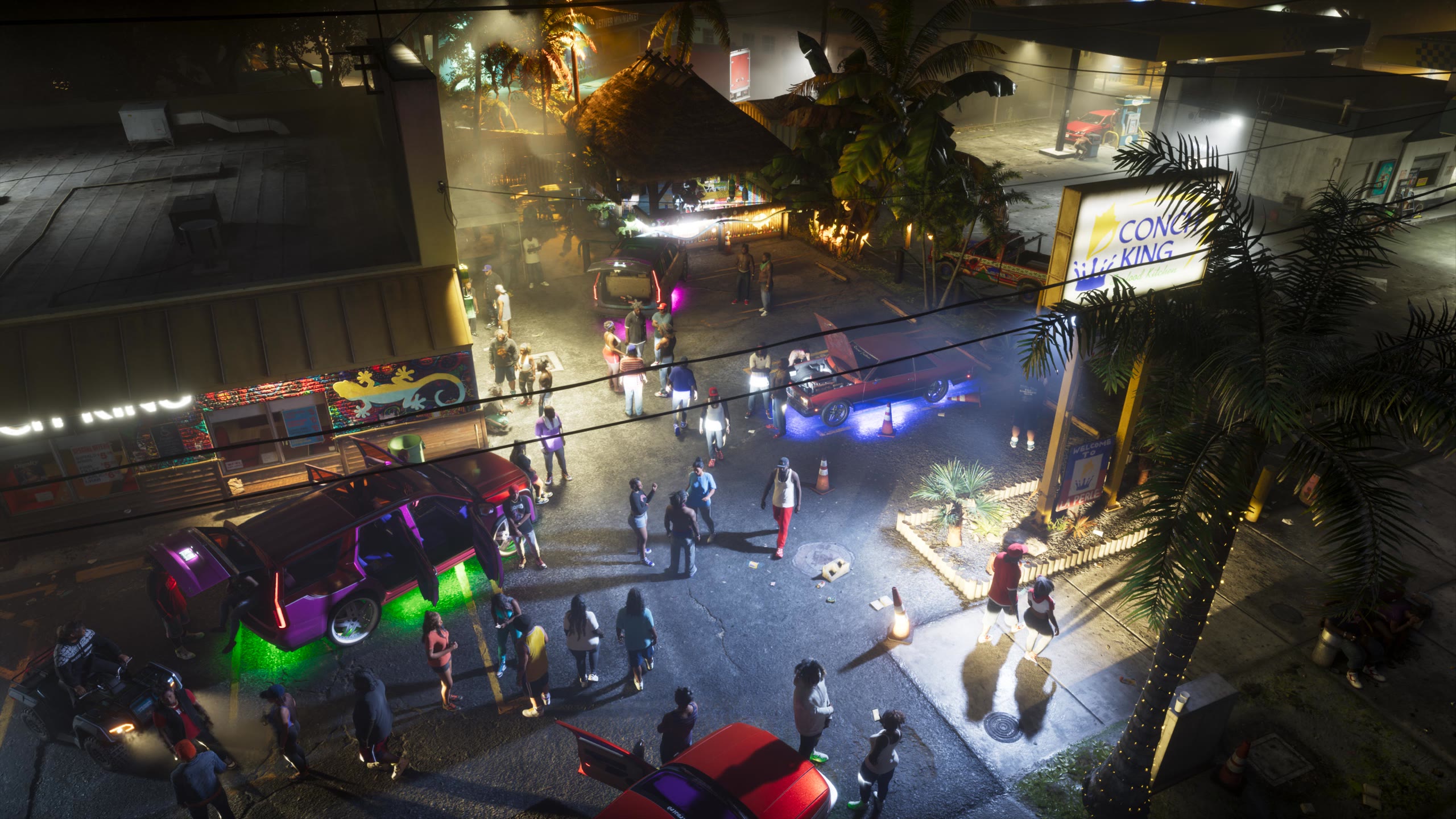 Vue en plongée d’une rue de Vice City la nuit, avec une foule, des voitures aux néons et des palmiers