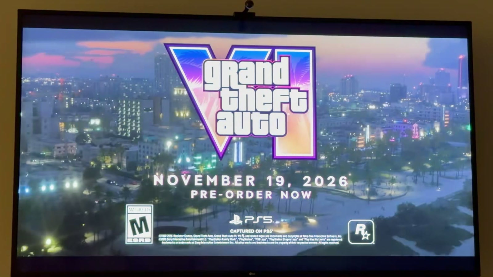 Écran final du spot TV de GTA VI filmé sur un téléviseur : logo Grand Theft Auto VI, date du 19 novembre 2026, mention Pre-order now, logos ESRB M, PS5 et Rockstar Games