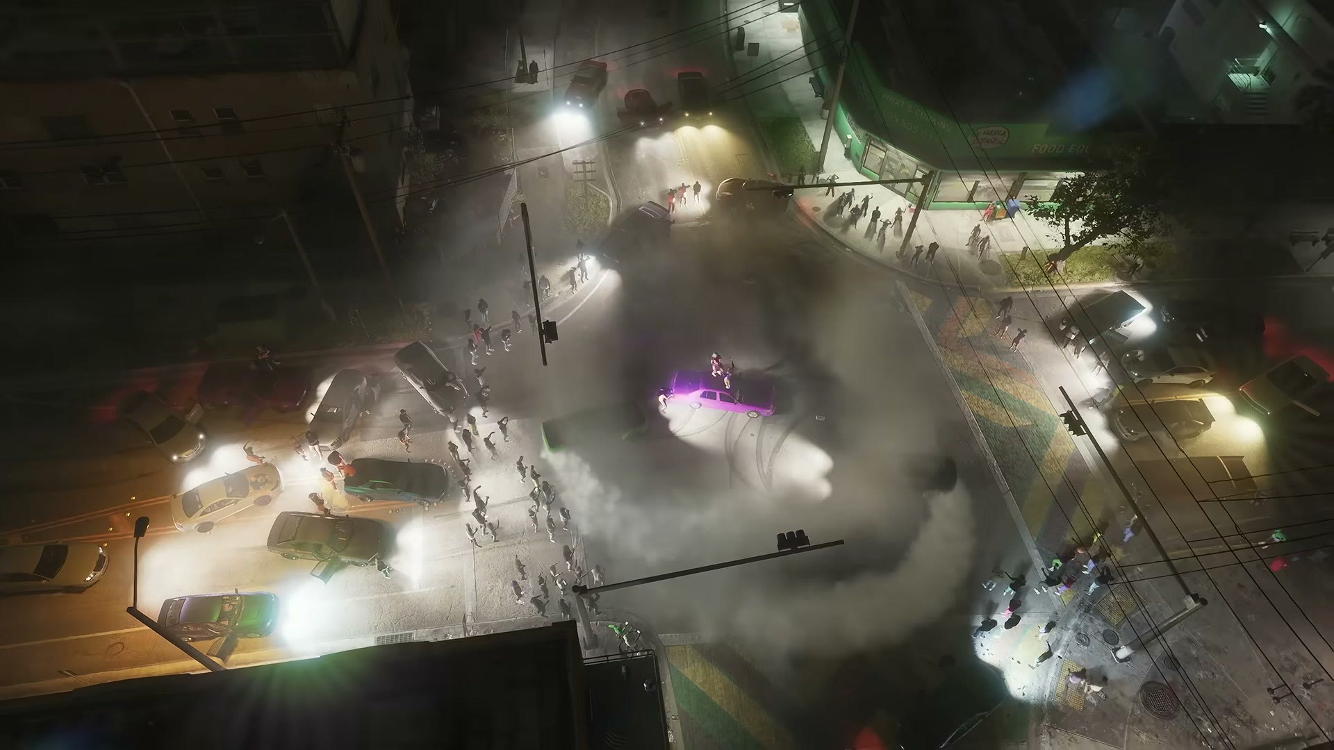Vue aérienne nocturne d’une voiture qui fait des dérapages au milieu d’un carrefour entouré d’une foule et de voitures, dans le Trailer 1 de GTA VI