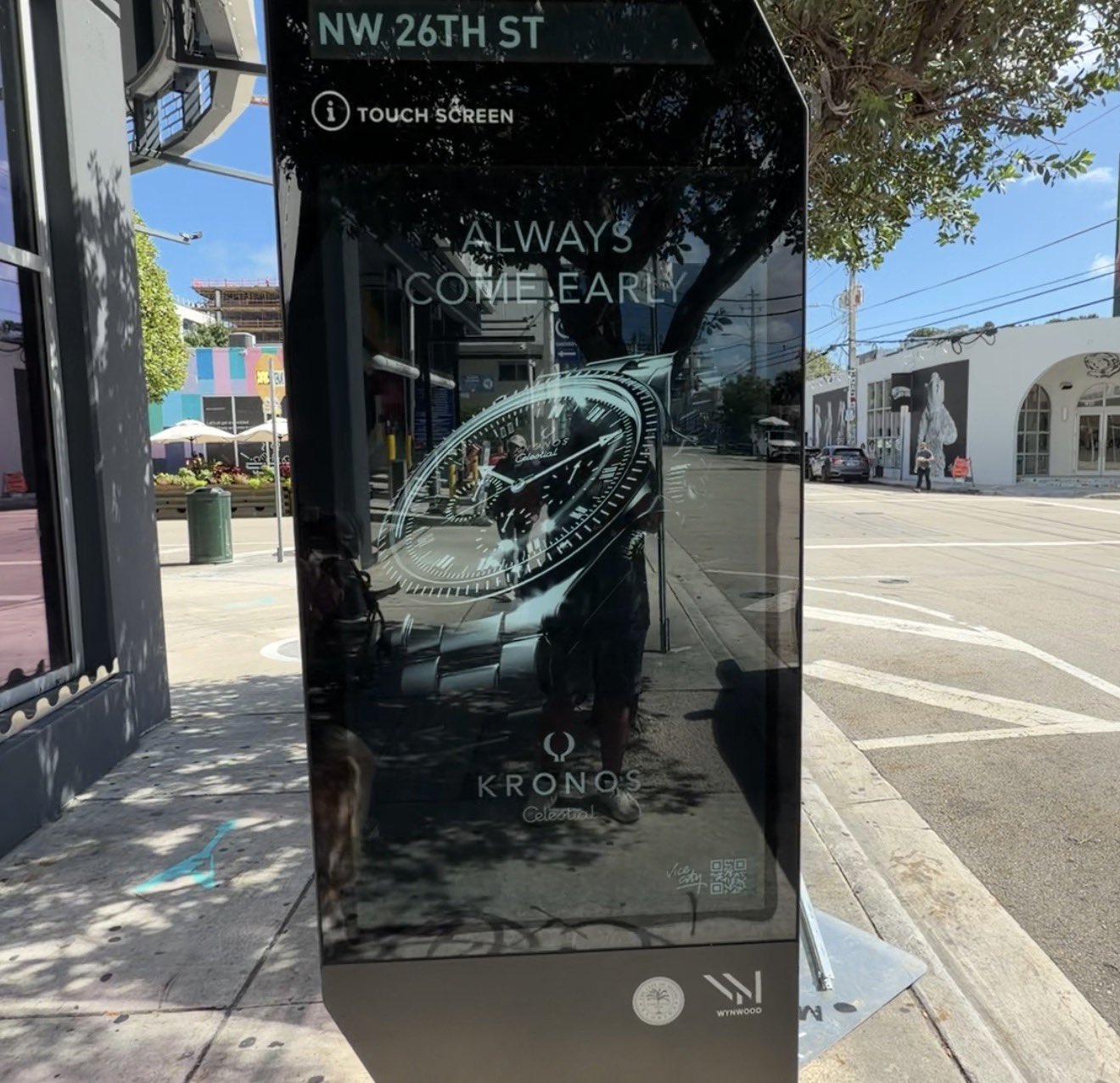 Borne de NW 26th Street à Wynwood affichant une montre Kronos Celestial et le slogan « Always come early », marque fictive de GTA VI
