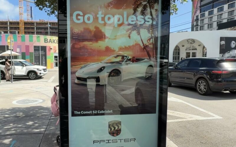 Borne numérique de NW 26th Street à Wynwood affichant une publicité « Go topless. » pour la Pfister Comet S2 Cabriolet de GTA VI, avec le logo Vice City