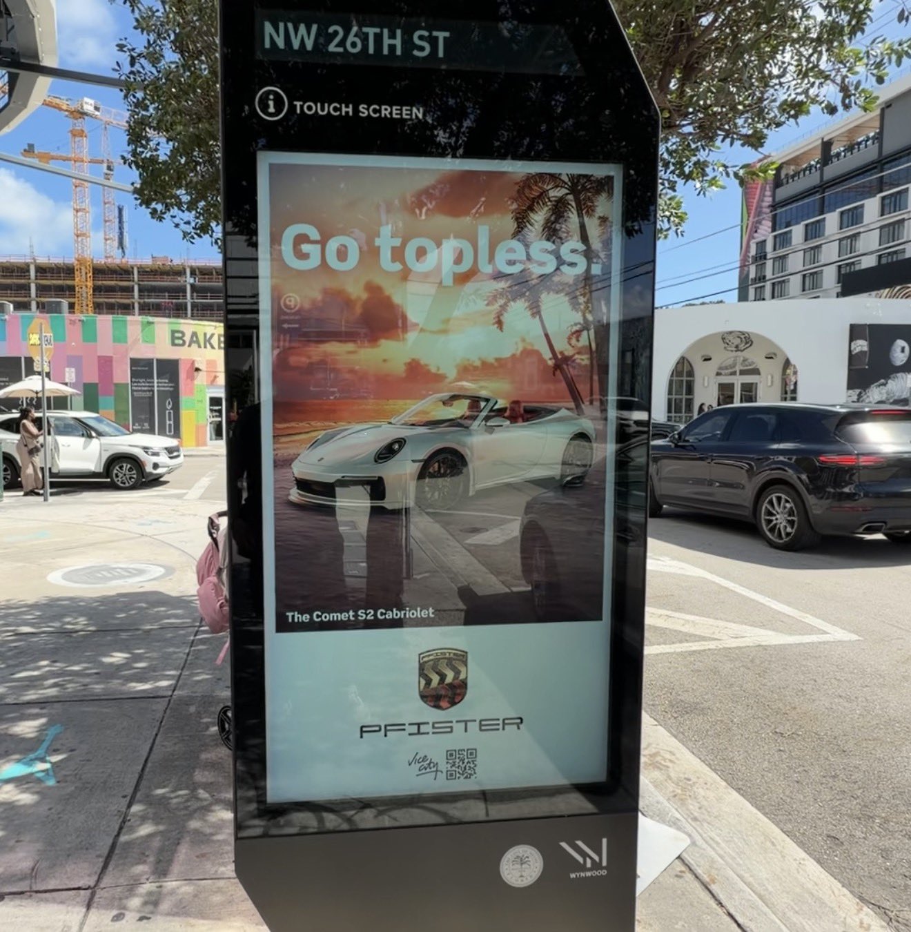 Borne numérique de NW 26th Street à Wynwood affichant une publicité « Go topless. » pour la Pfister Comet S2 Cabriolet de GTA VI, avec le logo Vice City