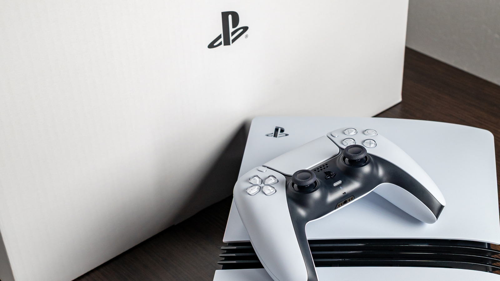 Une PS5 Pro blanche posée à plat avec une manette DualSense, devant son carton PlayStation
